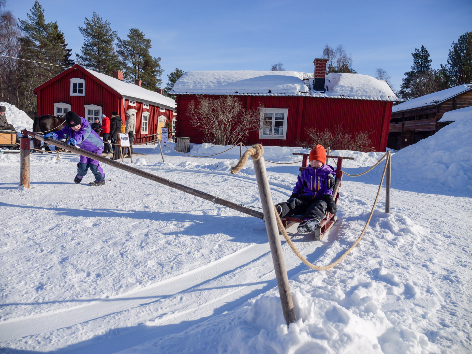 Två barn åker slängkälke utomhus i snön.